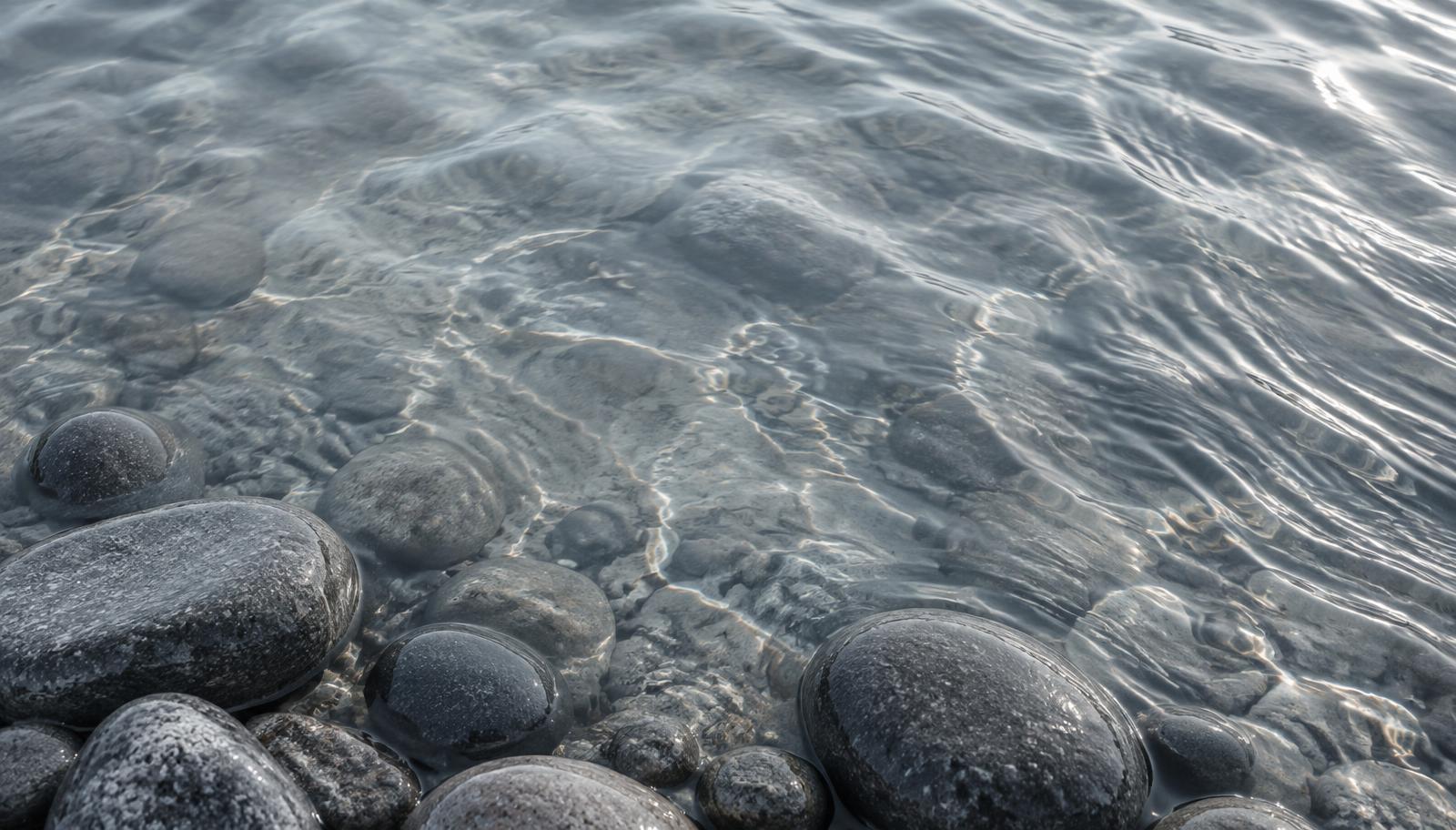 Calm water with soft ripples and smooth river stones