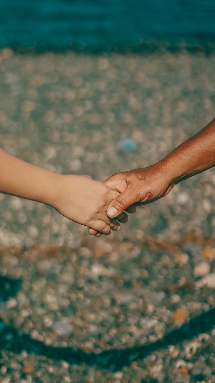 An adult and child holding hands